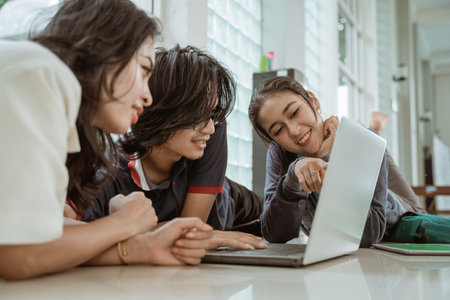 Portrait fun students lying down working in groupsの写真素材