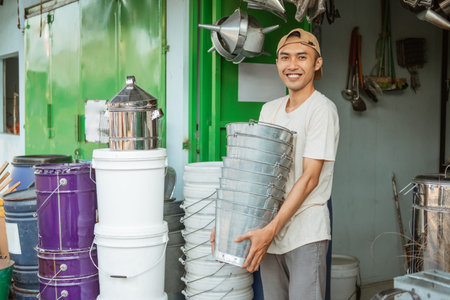 close up of asian male smiling while carrying lots of buckets