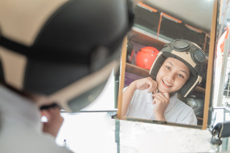 young women choose and wear helmets when they look in the mirrorの写真素材