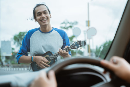 busker holding the ukulele is visible from the front of the windshield when the carの写真素材