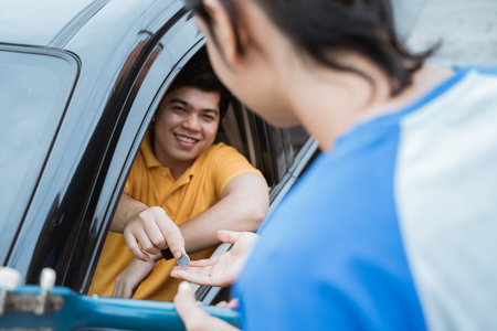 the man smiling from inside the car giving coin by hand from the car window to buskersの写真素材