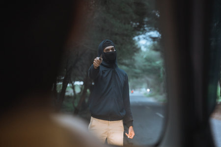 man in a mask uses a knife to threaten the car driver