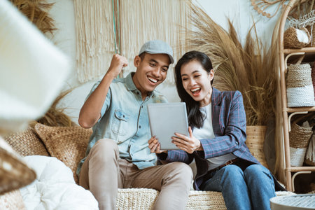 Asian young man and woman surprised when using digital tablets in craft shopsの写真素材