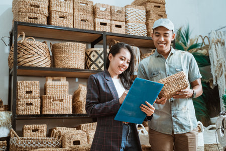 asian woman holds the clipboard and the man holds the wicker box while checking itemsの写真素材