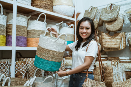 woman smiles at the camera as she raises a woven basketの写真素材