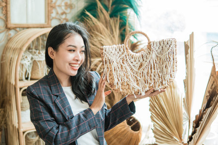 beautiful woman in blazer carries and looks at woven bagの写真素材