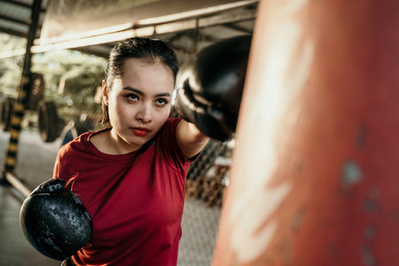 woman boxer fighter doing exercise hitting punching bag with copyspaceの写真素材