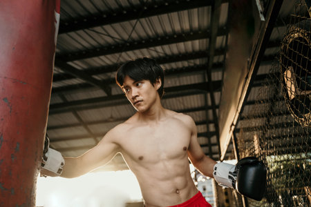 asian man boxer during boxing hiting heavy bagの写真素材