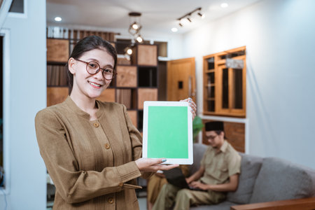 female teacher in a civil servant uniform wearing glasses smiling while showing a digital tabletの写真素材