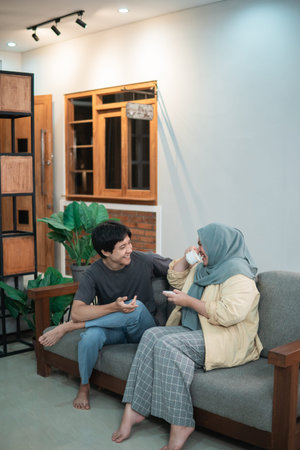 hooded girl and an asian boy chat after coffee in the living room