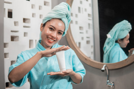Beautiful asian young woman face holding and presenting cream tube productの写真素材