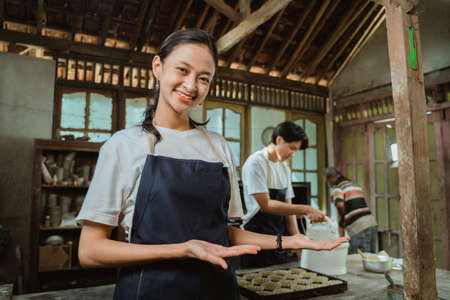 Beautiful employee in apron offering you something from her palmsの写真素材