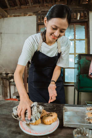 The girl making the cake in an apron using a cloth towel takes the freshly baked cake on the tableの写真素材