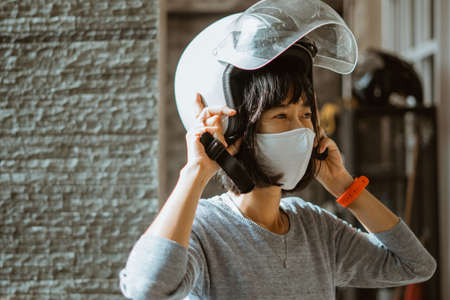 woman wearing helmet and mask getting ready to ride motorbikeの写真素材