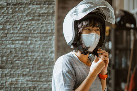 woman wearing helmet and mask getting ready to ride motorbikeの写真素材