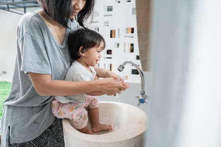 Asian toddler baby child washing cleaning hands with momの写真素材