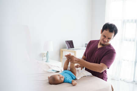 asian father changing his infant baby diaperの写真素材