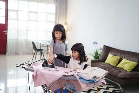 girl smiling happily as she doing the ironing at homeの写真素材