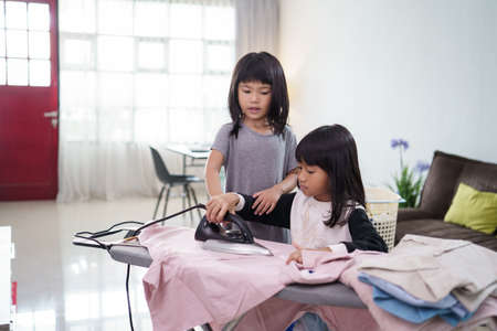 girl smiling happily as she doing the ironing at homeの写真素材