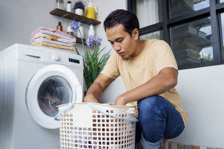 Housework. asian Man loading clothes into washing machineの写真素材