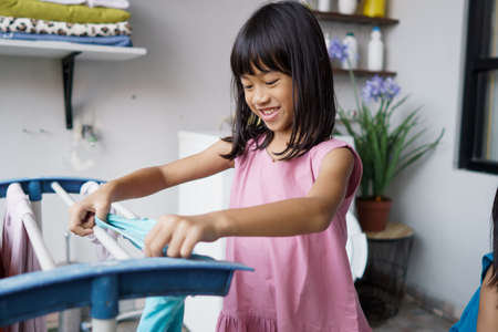 little asian girl doing laundry at homeの写真素材