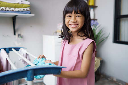 little asian girl doing laundry at homeの写真素材