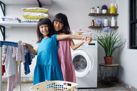 child fun happy little girl to wash clothes and laughs in the laundry roomの写真素材