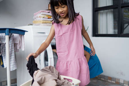 little asian girl doing laundry at homeの写真素材