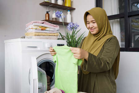Woman in hijab doing clothing ironing at homeの写真素材