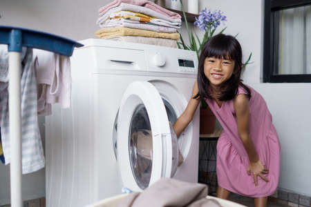 little asian girl doing laundry at homeの写真素材