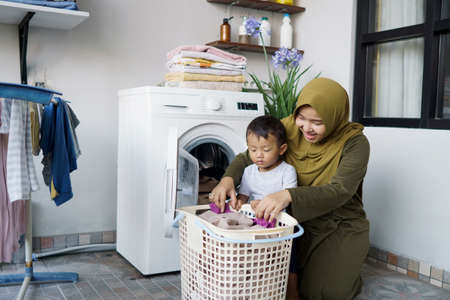 muslim asian woman doing laundry with her sonの写真素材