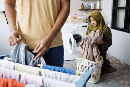 muslim woman and her husband doing laundry togetherの写真素材