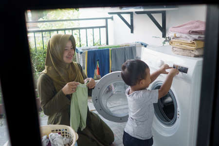 mother a housewife with a baby engaged in laundryの写真素材
