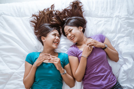 young adult asian twin sister together on the bed