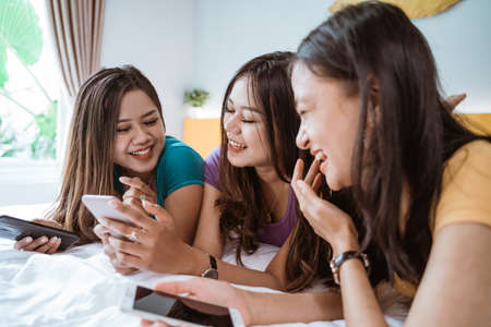 three asian girl friends hanging out together making video callの写真素材