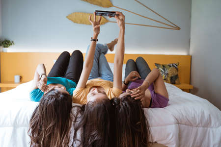woman taking photo of her friends using phone while hanging out togetherの写真素材