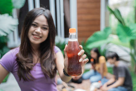 friends having fun while eating and drinking in the backyard - showing blank bottle to cameraの写真素材