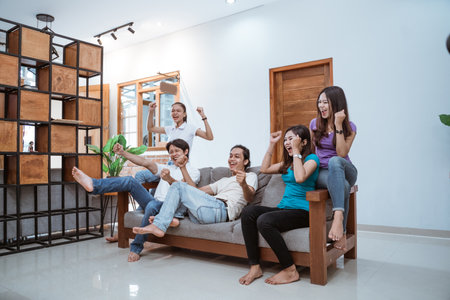 friends watching TV and cheering soccerの写真素材