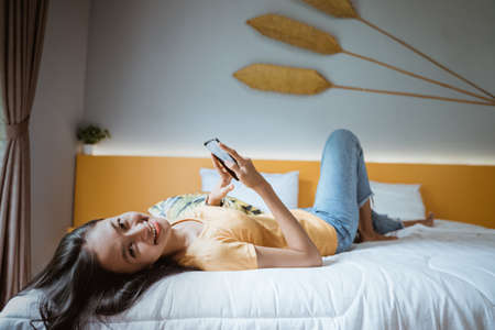 Happy attractive asian young woman using cellphone at homeの写真素材