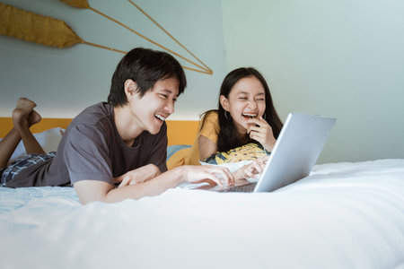 couple relaxing on bed using the laptop at home in the bedroomの写真素材