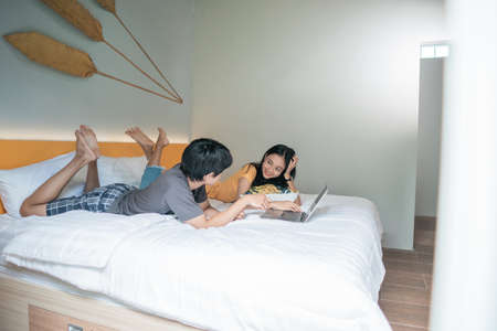 couple relaxing on bed using the laptop at home in the bedroomの写真素材