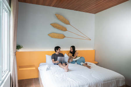couple relaxing on bed using the laptop at home in the bedroomの写真素材
