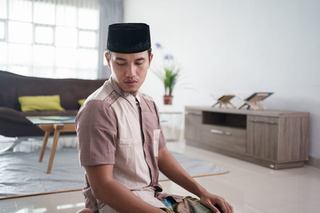 Young Muslim man praying at home