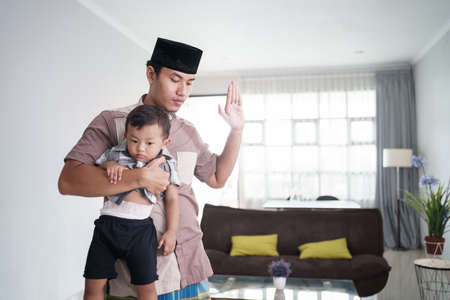 muslim father praying at home while babysit his sonの写真素材
