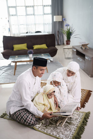 happy muslim family with children reading quran and pray togetherの写真素材
