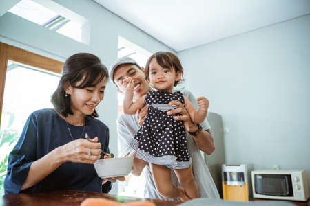 happy asian father mother and daughter cooking together in modern kitchenの写真素材