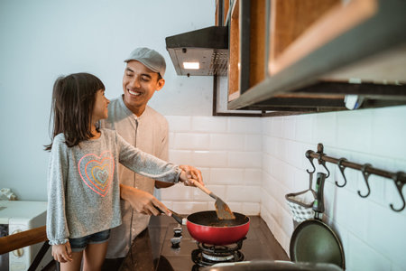 happy asian father and daughter cooking together in modern kitchen