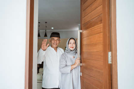 muslim asian senior couple standing at front door waiting for familyの写真素材