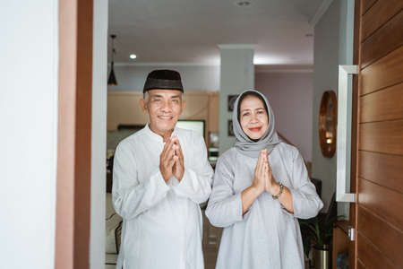 muslim asian senior couple standing at front door waiting for familyの写真素材