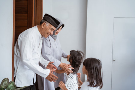 asian muslim aged couple meeting kids and grand children at doorstep during eid mubarakの写真素材